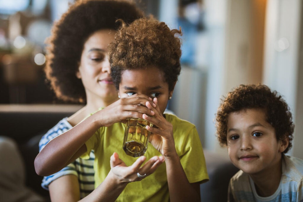 Little girl drinking lead-exposed water with her mom and sister.